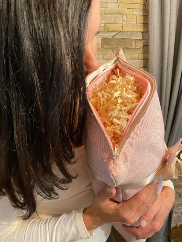 Zirbenkissen Geschenk für Frauen. Zirbenkissen mit Baumwollüberzug in Farbe rosé. Das geöffnete Kissen wird von einer Frau knapp ans Gesicht gehalten um am Zirbenduft zu riechen.