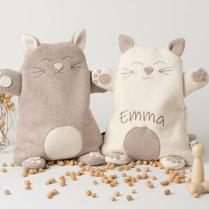 Wärmekissen Katze personalisiert in Farbe creme. Der Name des Kindes (in diesem Fall "Matteo") wurde mit braunem Stickgarn in 4 cm großen Buchstaben in den Bauch eingestickt. Die Katze hat abstehende Ohren, Pfoten und einen Schweif. Abbildung der Vorderseite. Überzug sowie das Innenkissen sind pflegeleicht waschbar.