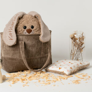 Geschenk zur Taufe -personalisiert-handgefertigt-waschbar-Steirerkissen. Das Set besteht aus einer braunen Cordstoff-Baumwolltasche mit Henkeln, ein Zirbenkissen Hase in brauner Farbe mit Zirbenfüllung und ein Kirschkernkissen passend zur Tasche. Der Hase ist hergestellt aus Baumwoll-Plüschstoff kombiniert Baumwoll-Vlies mit abstehenden Ohren in sitzender Position. Die Kulleraugen, die Schnauze, Barthaare sowie die Hinterpfoten sind aus Vliesstoff aufgenäht. Die Vorderpfoten stehen seitlich ab.